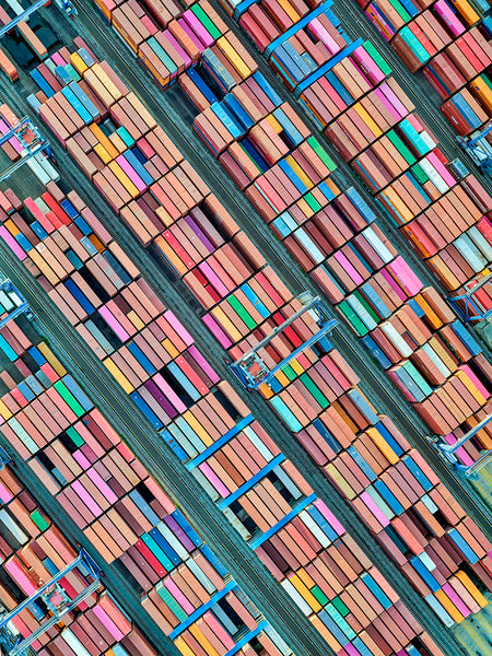 Aerial images by Jeffrey Milsteins Newark Port 10 reveal a bustling shipping yard, with colorful containers arranged in precise, vibrant geometric patterns. High-resolution cameras capture the vivid hues of orange, pink, blue, and green containers in perfect alignment.